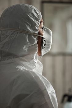 一名医护人员在室内佩戴个人防护装备和口罩的侧面轮廓，强调了安全性