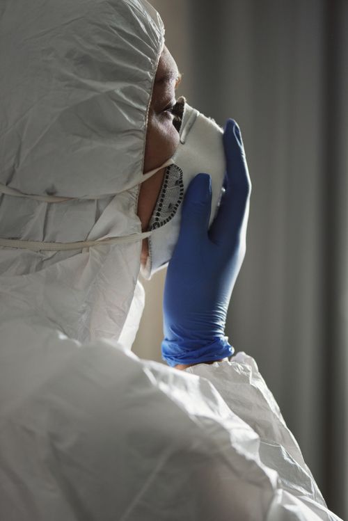 Free Healthcare professional in full PPE adjusting face mask during work. Stock Photo