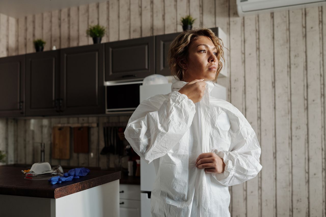 woman in personal protective equipment zipping up suit in a kitchen se