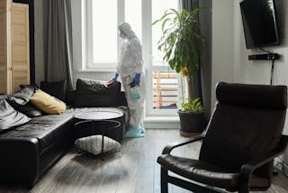 A Woman Wearing Personal Protective Equipment Cleaning the House