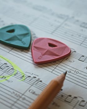 Close-up of colorful guitar picks on a music sheet with a pencil, highlighting musical artistry.