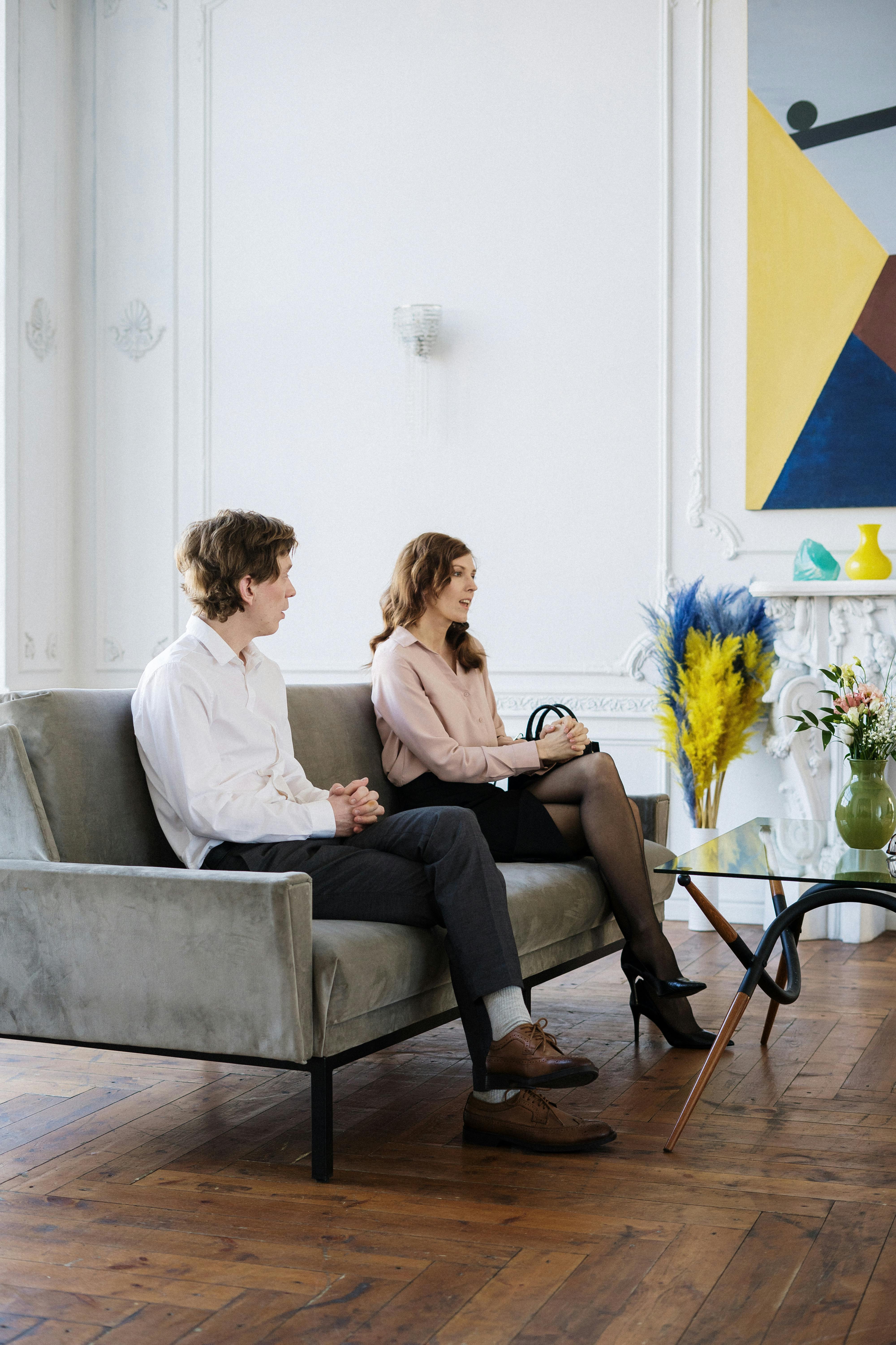 2 women sitting on gray sofa