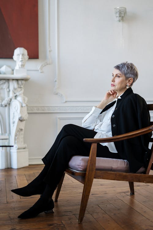 Woman in Black Blazer Sitting on Brown Wooden Armchair
