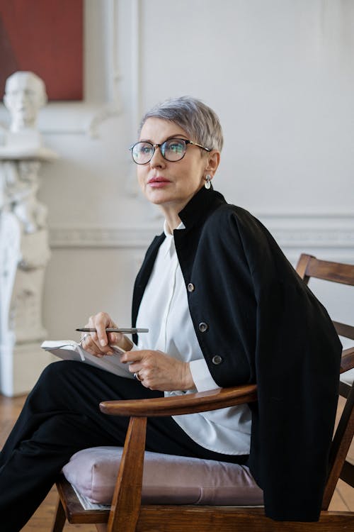 Woman in Black Blazer Sitting on Brown Wooden Chair