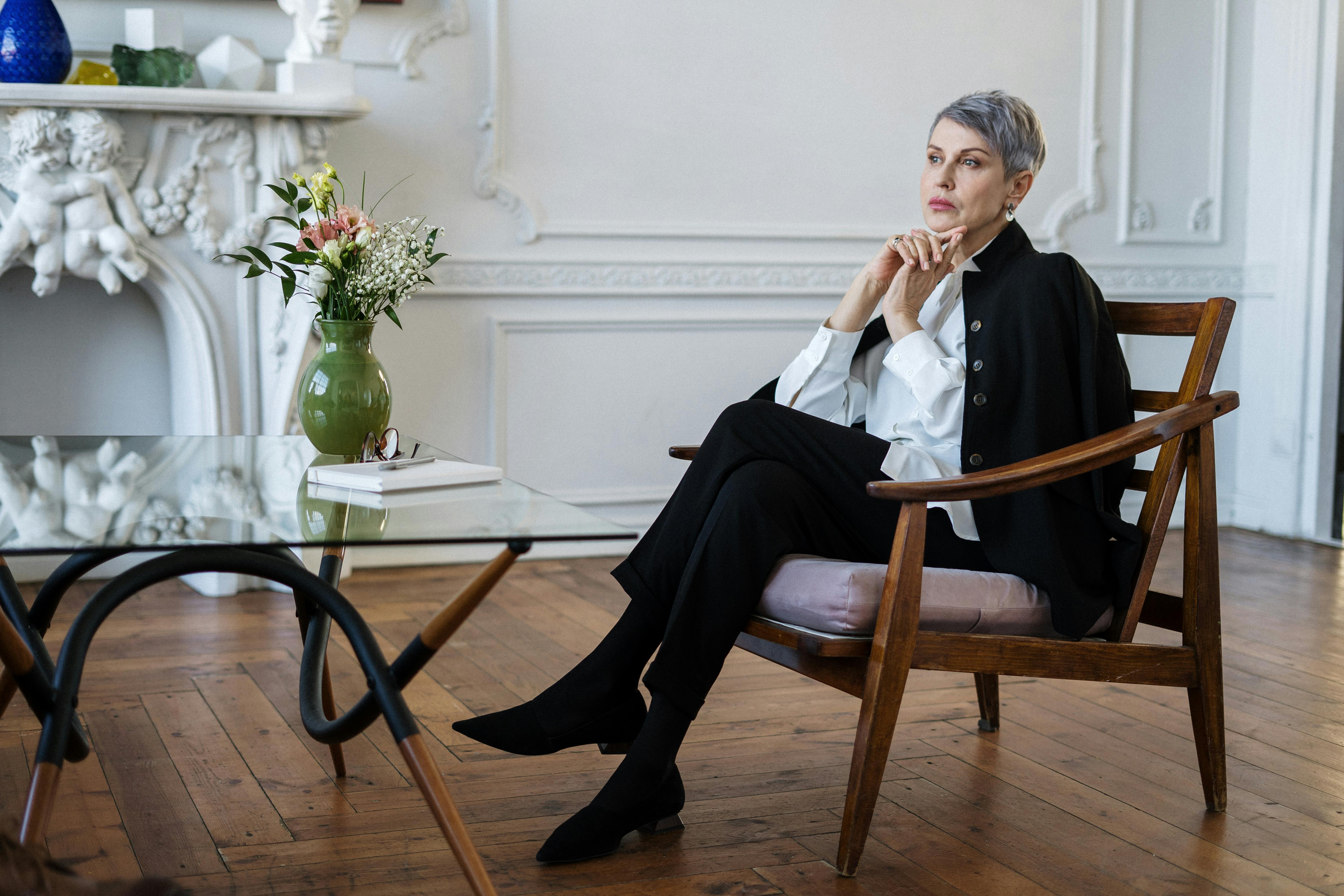 woman in black and white long sleeve shirt sitting on brown wooden chair