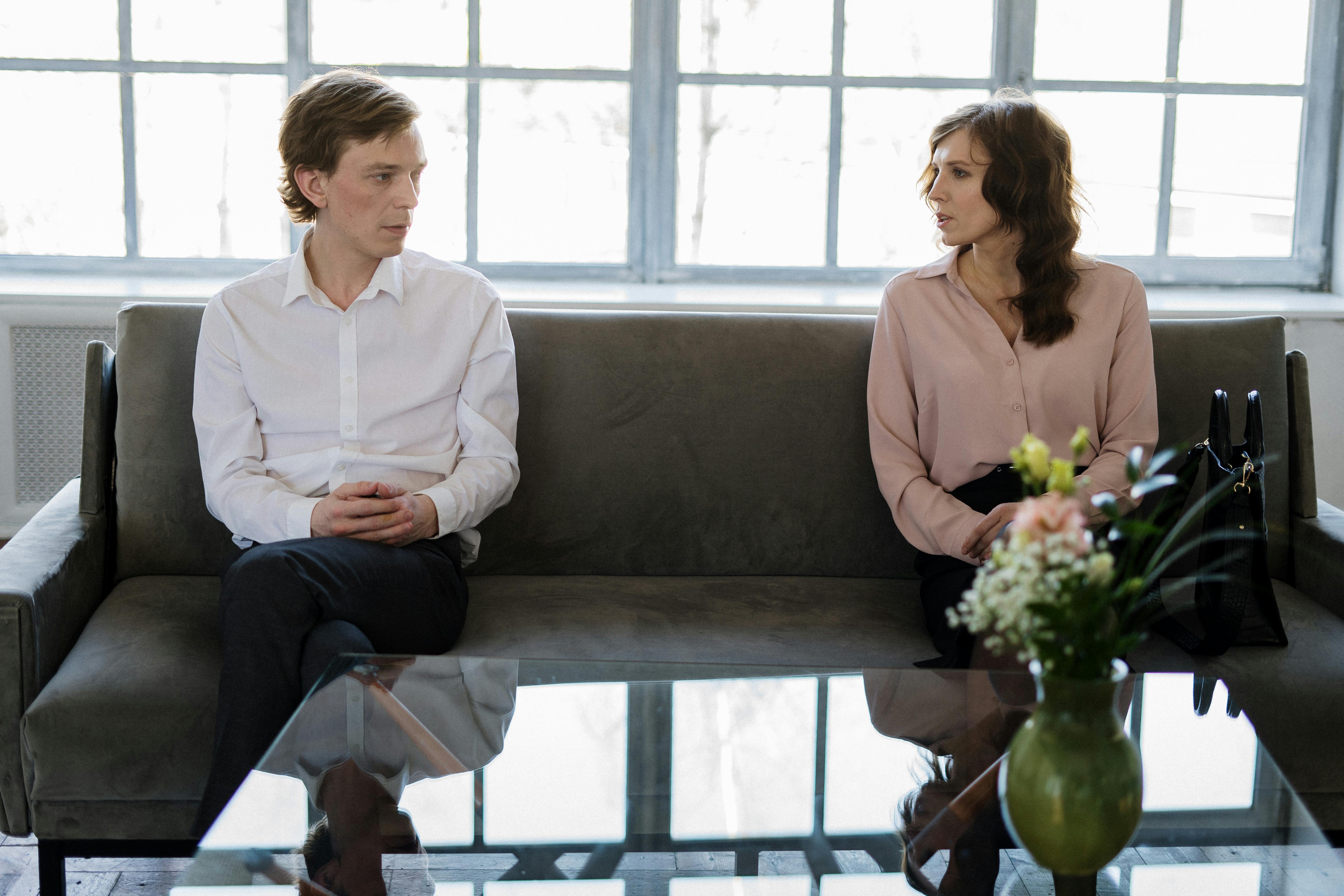 man and woman sitting on gray couch