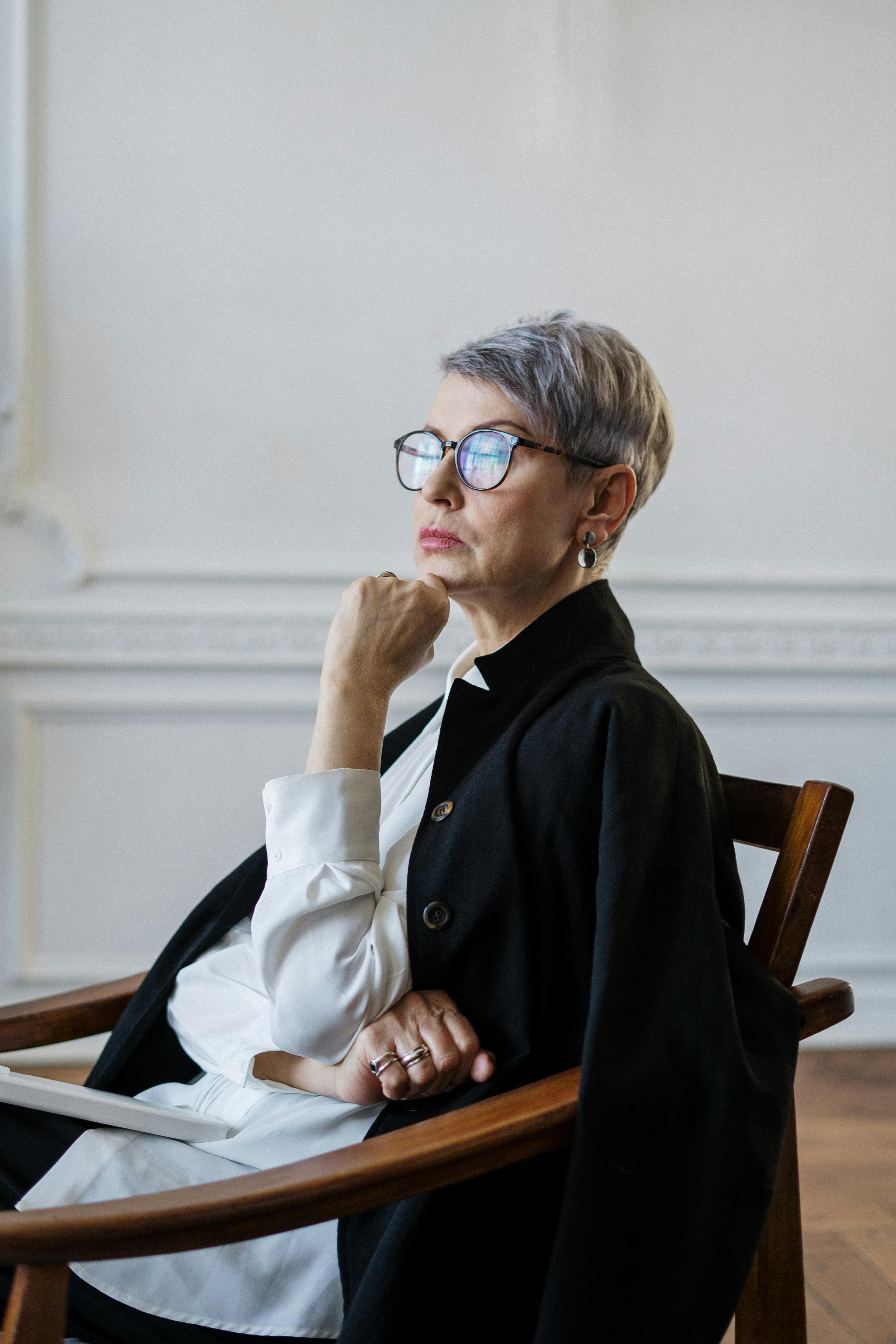 woman in black coat sitting on brown wooden chair