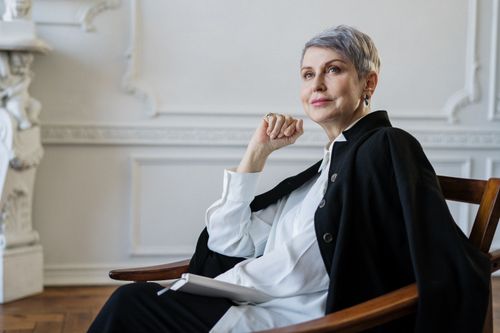 Free Senior woman with short hair seated indoors, exuding confidence and elegance in a classic setting. Stock Photo