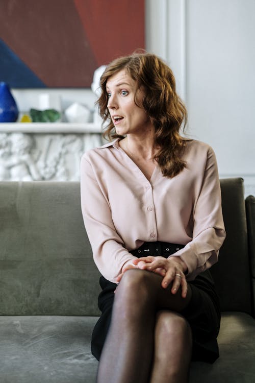 Woman in Pink Button Up Long Sleeve Shirt Sitting on Gray Couch