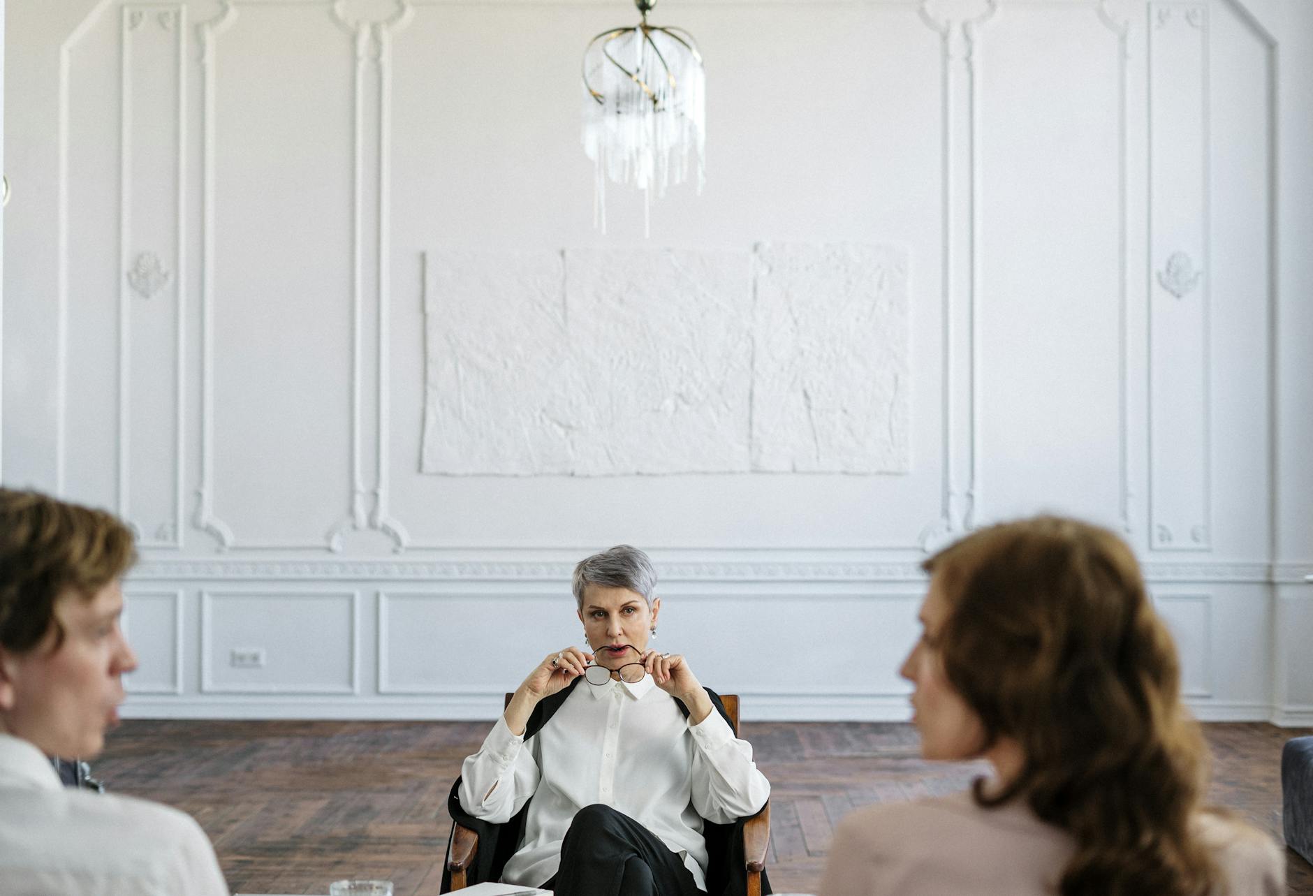 Woman in White Long Sleeve Shirt Sitting on Brown Wooden Floor