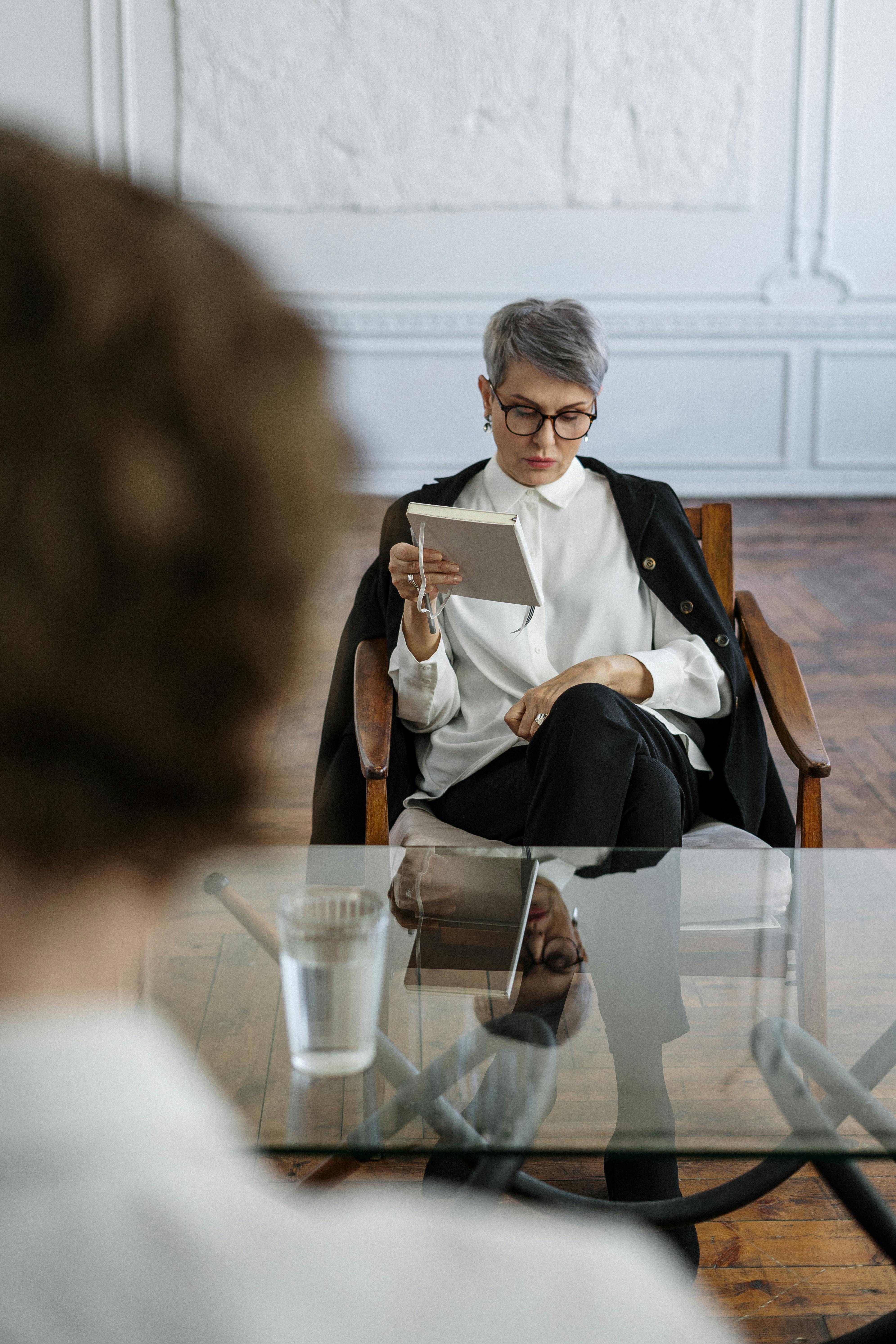 woman in black blazer sitting on brown wooden chair