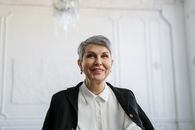 一位身着正装、面带微笑的成熟女性在室内显得十分自信