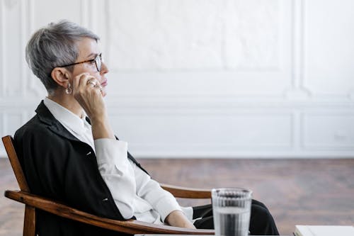 Man in White Dress Shirt Wearing Eyeglasses Sitting on Chair