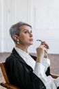 一位资深女性戴着眼镜沉思，反思现代办公室