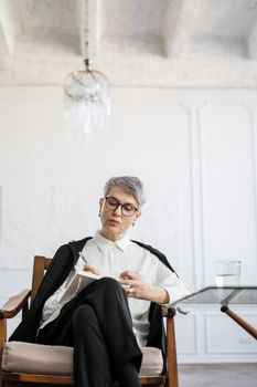 一位成熟的女性坐在现代化的办公室里，沉思着自己的想法