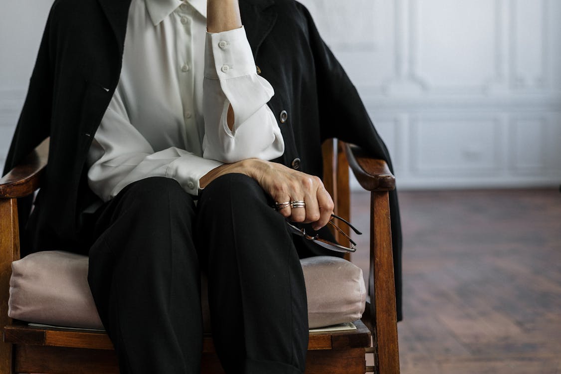 Man in Black Suit Sitting on Brown Wooden Armchair