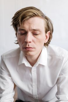 一位沉思的成年男子穿着白衬衫的特写肖像，传达着情感