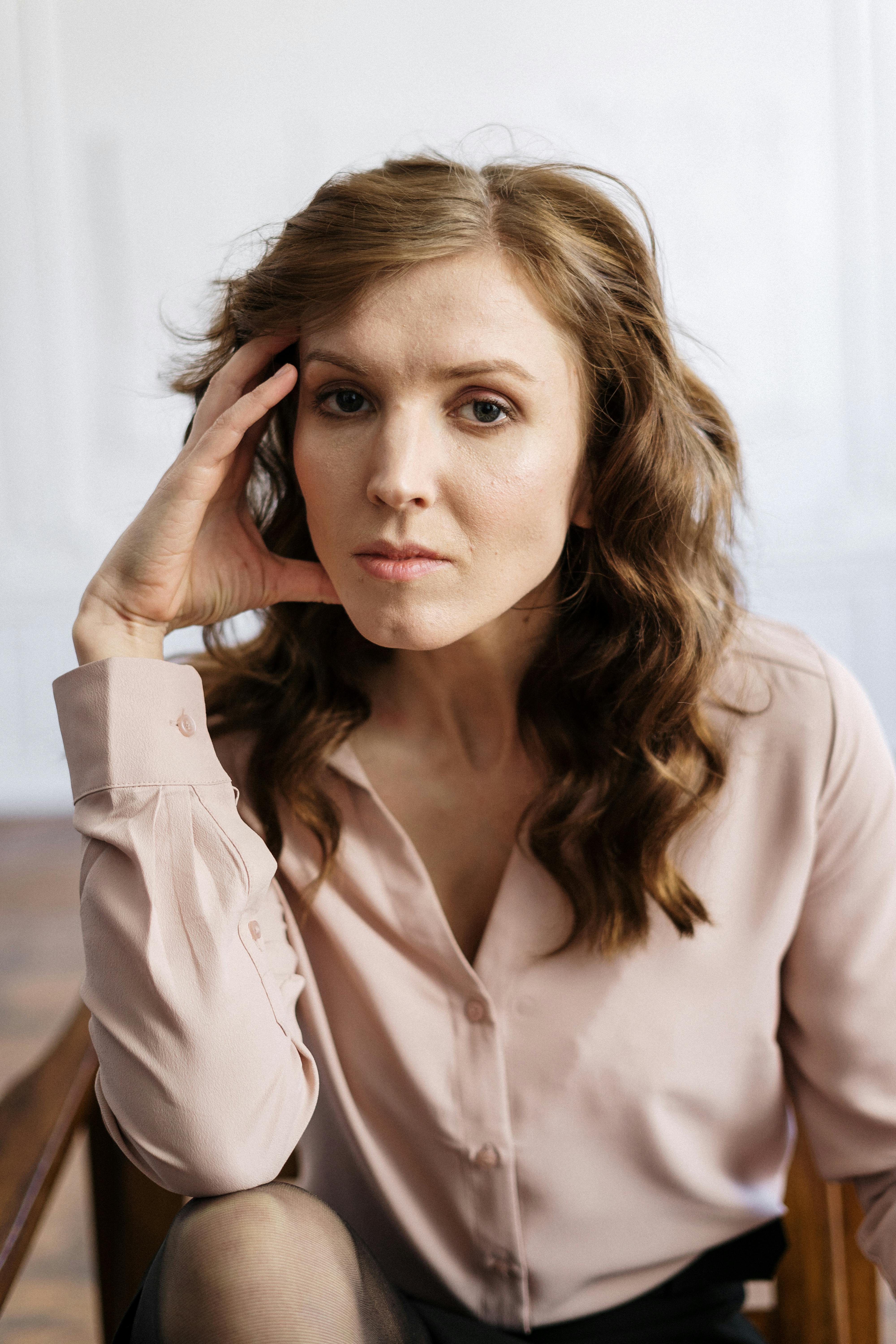 woman in white button up shirt holding her hair