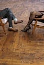 Person in Black Leather Shoes Sitting on Brown Wooden Chair