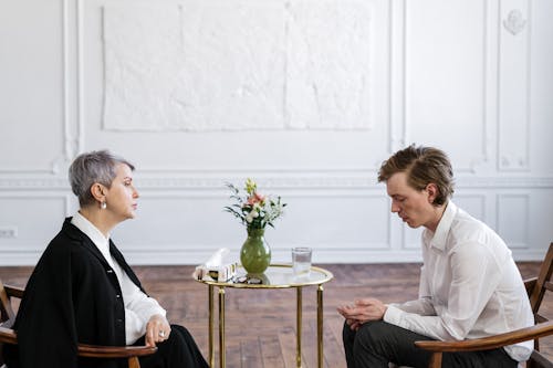 Man in White Dress Shirt Sitting Beside Woman in Black Dress