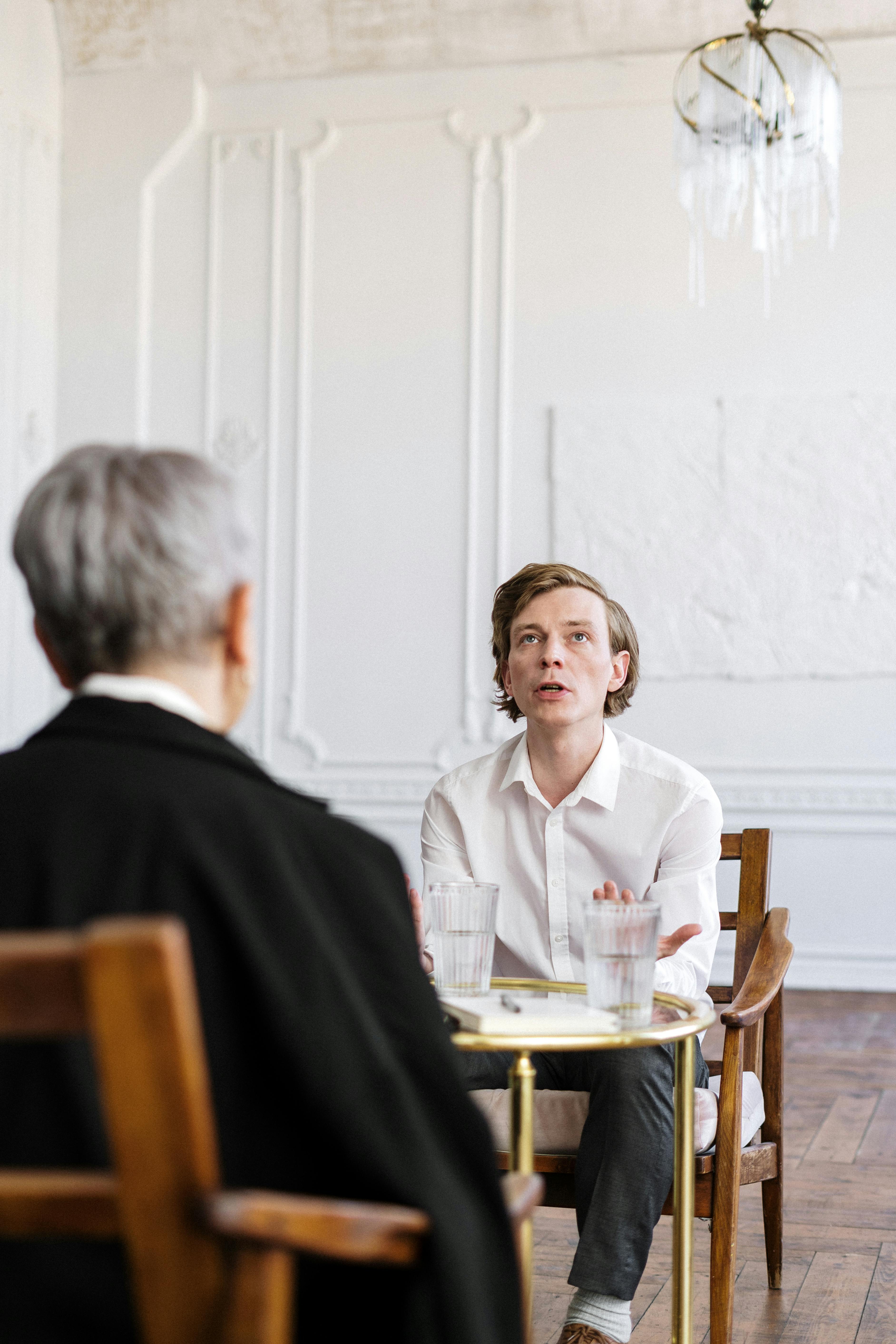 man in black suit sitting beside woman in white dress shirt