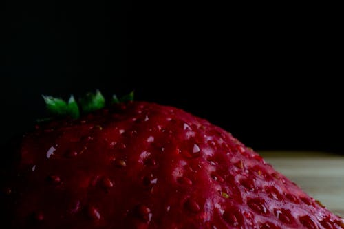 High angle closeup of fresh ripe juicy strawberry placed on table against black background