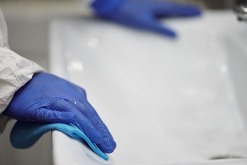 Free Person in Blue Gloves Cleaning White Sink Stock Photo