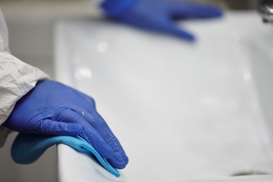 Person in Blue Gloves Cleaning White Sink