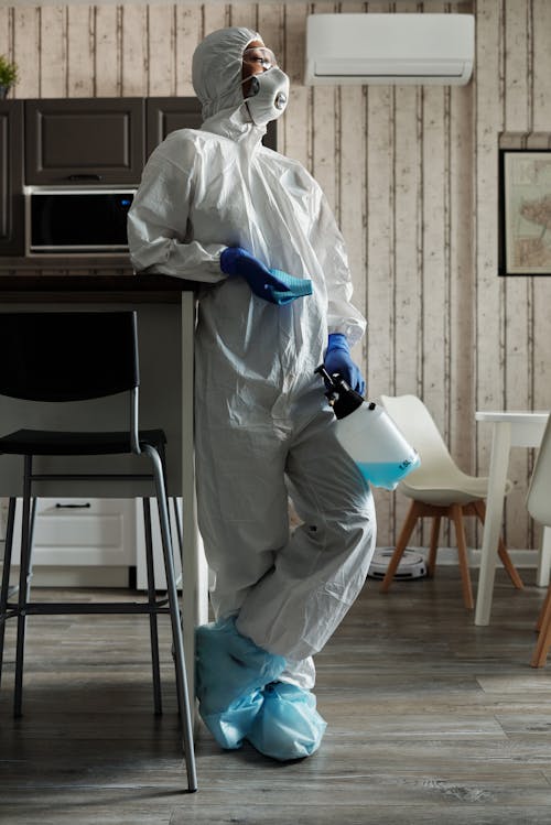 Free Person in White PPE Holding Spray Bottle Stock Photo