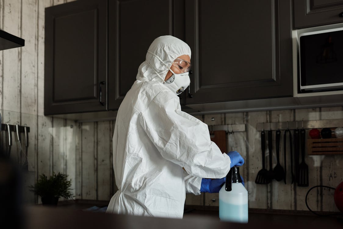 Free Person In White Ppe Closing The Spray Bottle Stock Photo