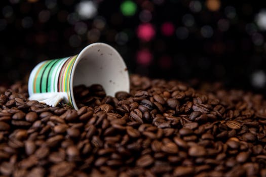 Close-up of a tipped mug spilling coffee beans against a bokeh background.