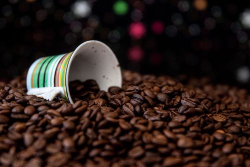 Free Close-up of a tipped mug spilling coffee beans against a bokeh background. Stock Photo