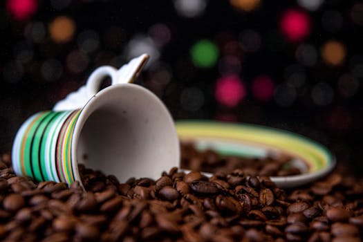 An artistic shot of a colorful ceramic mug resting on a bed of coffee beans, creating a vibrant still life scene.