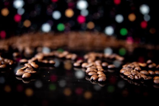 Close-up of coffee beans on black surface with colorful bokeh lights. Perfect for aromatic coffee themes.