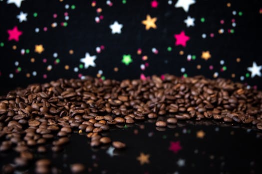 Aromatic coffee beans spread on a black surface with a colorful starry background.