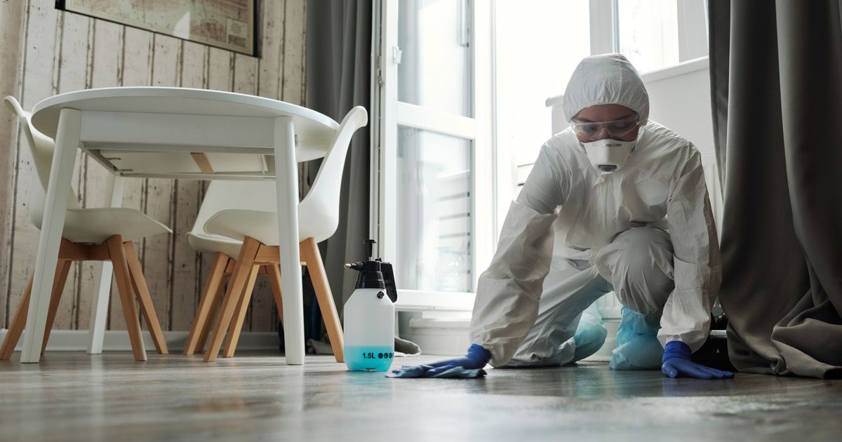 Reinigungskraft im Schutzanzug bei der Flächendesinfektion im kontrollierten Bereich