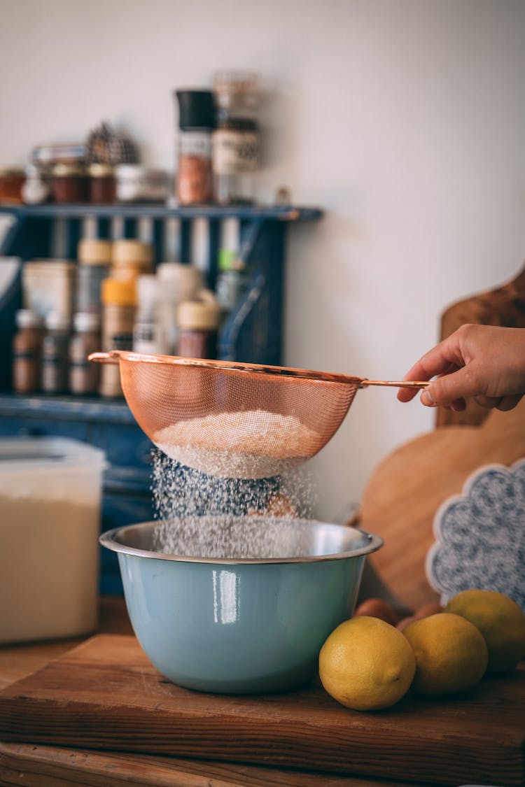 A Person Sifting The Flour