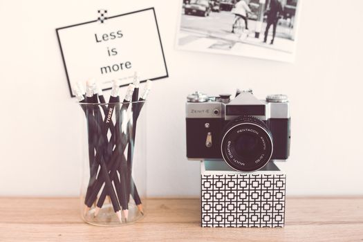A classic Zenit-E camera beside a jar of pencils and a 'Less is more' sign, exemplifying minimalist style.