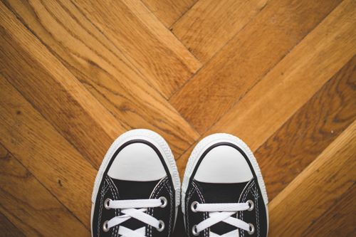 Free Close-up of black sneakers with white laces on a wooden parquet floor. Stock Photo