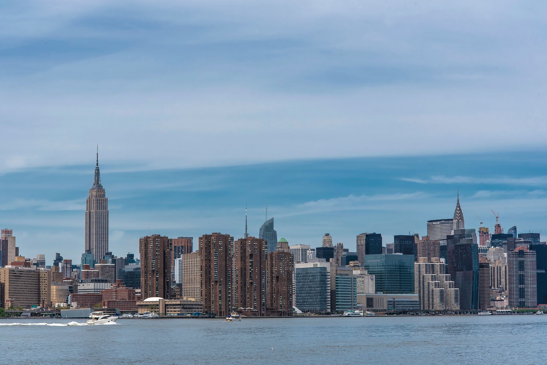 Panoramic view of New York City's skyline featuring iconic skyscrapers under a vibrant blue sky.
