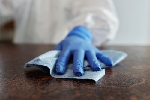 Free A hand wearing a blue glove wipes a surface with a cloth, emphasizing hygiene and cleanliness. Stock Photo