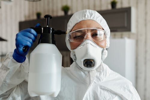 Woman in Protection Suit with Spray Bottle in Hand