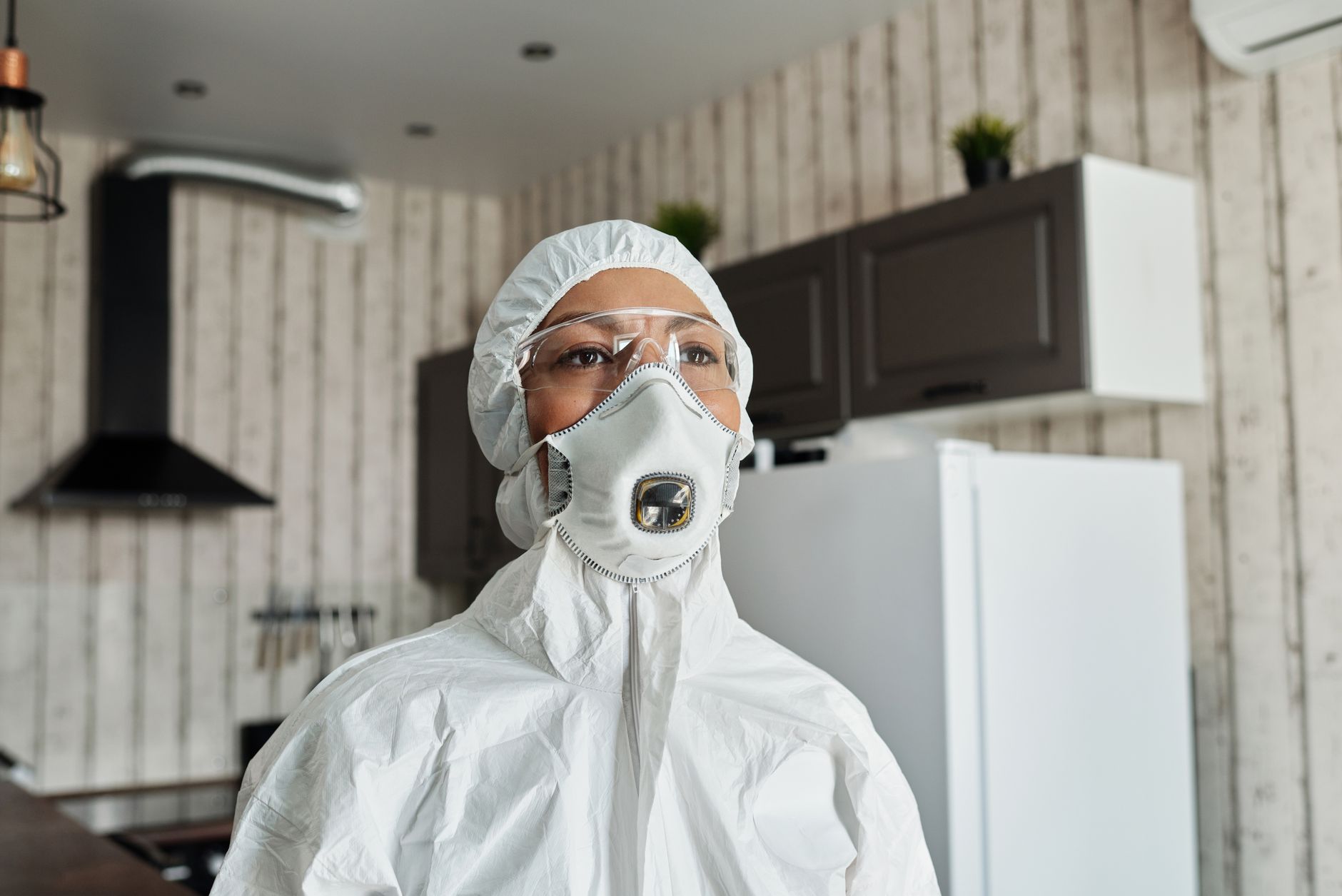 Healthcare professional in full protective suit and mask indoors for safety during pandemic.