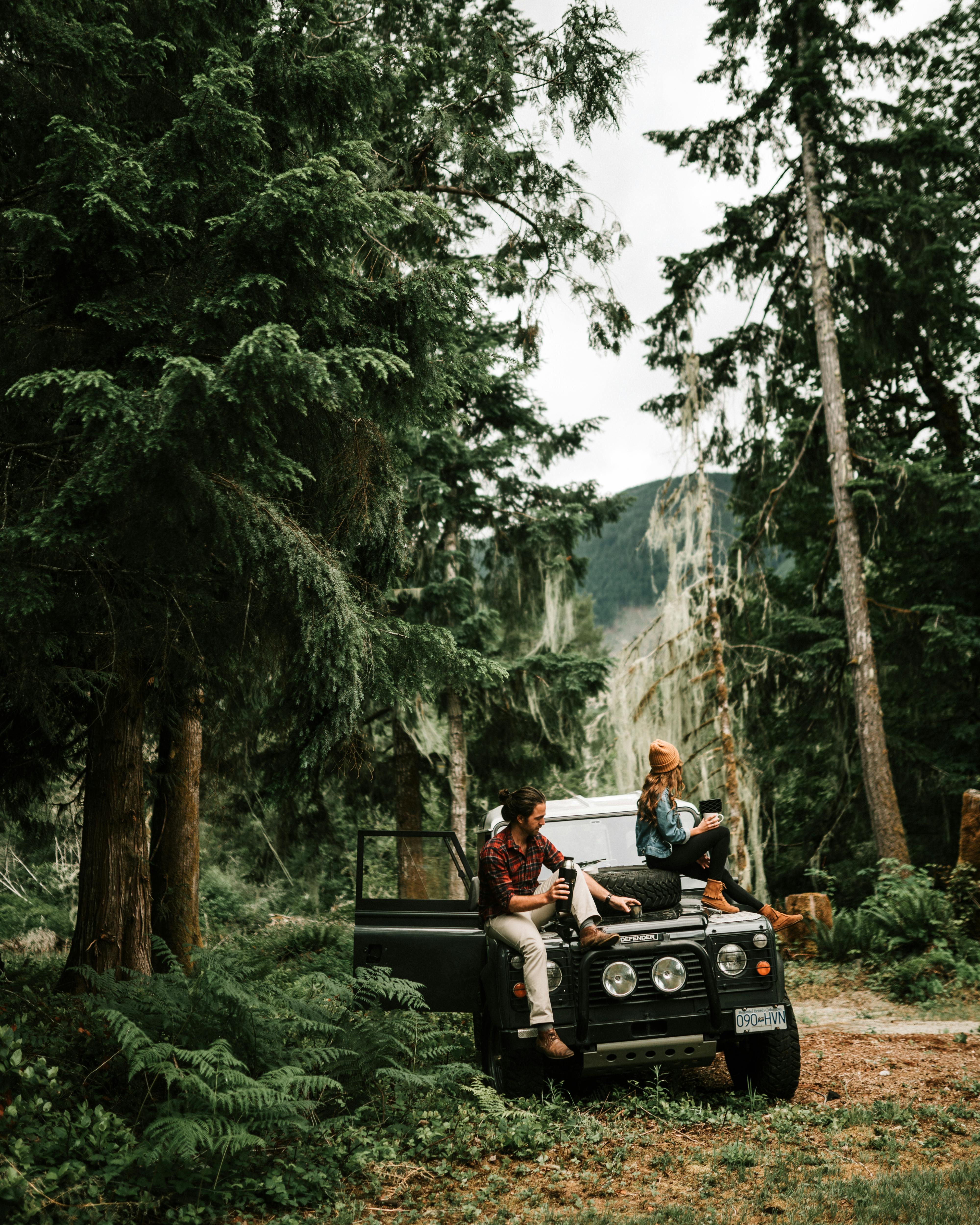 man and woman sitting on black jeep wrangler