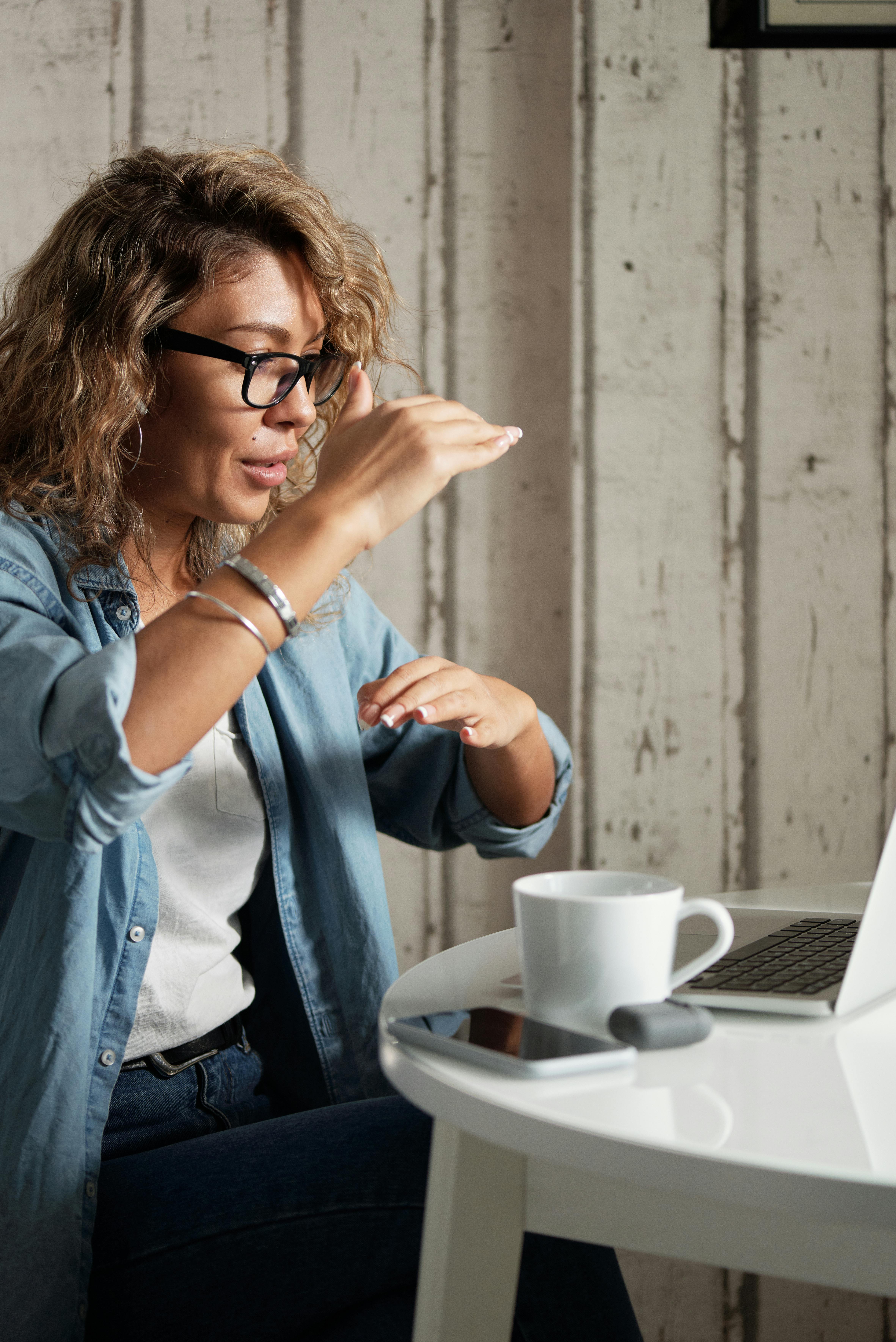 woman in blue denim jacket using a laptop