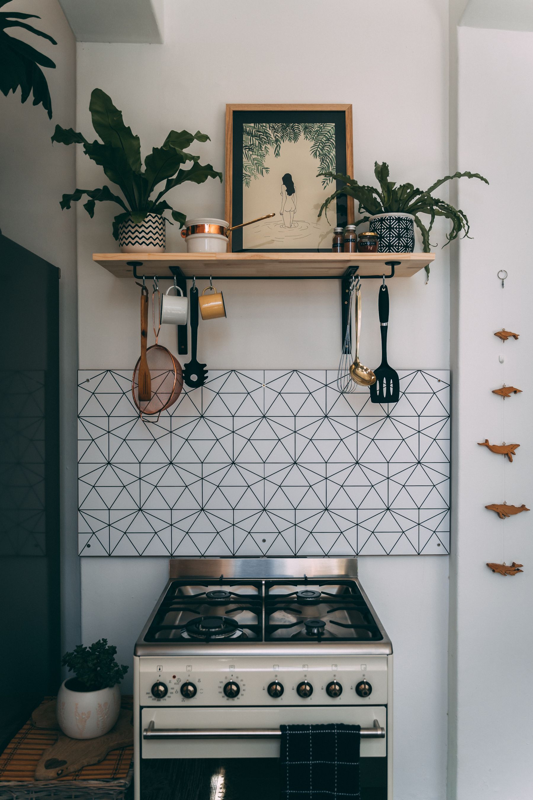 Working kitchen with a stove, light cabinetry and potted plants