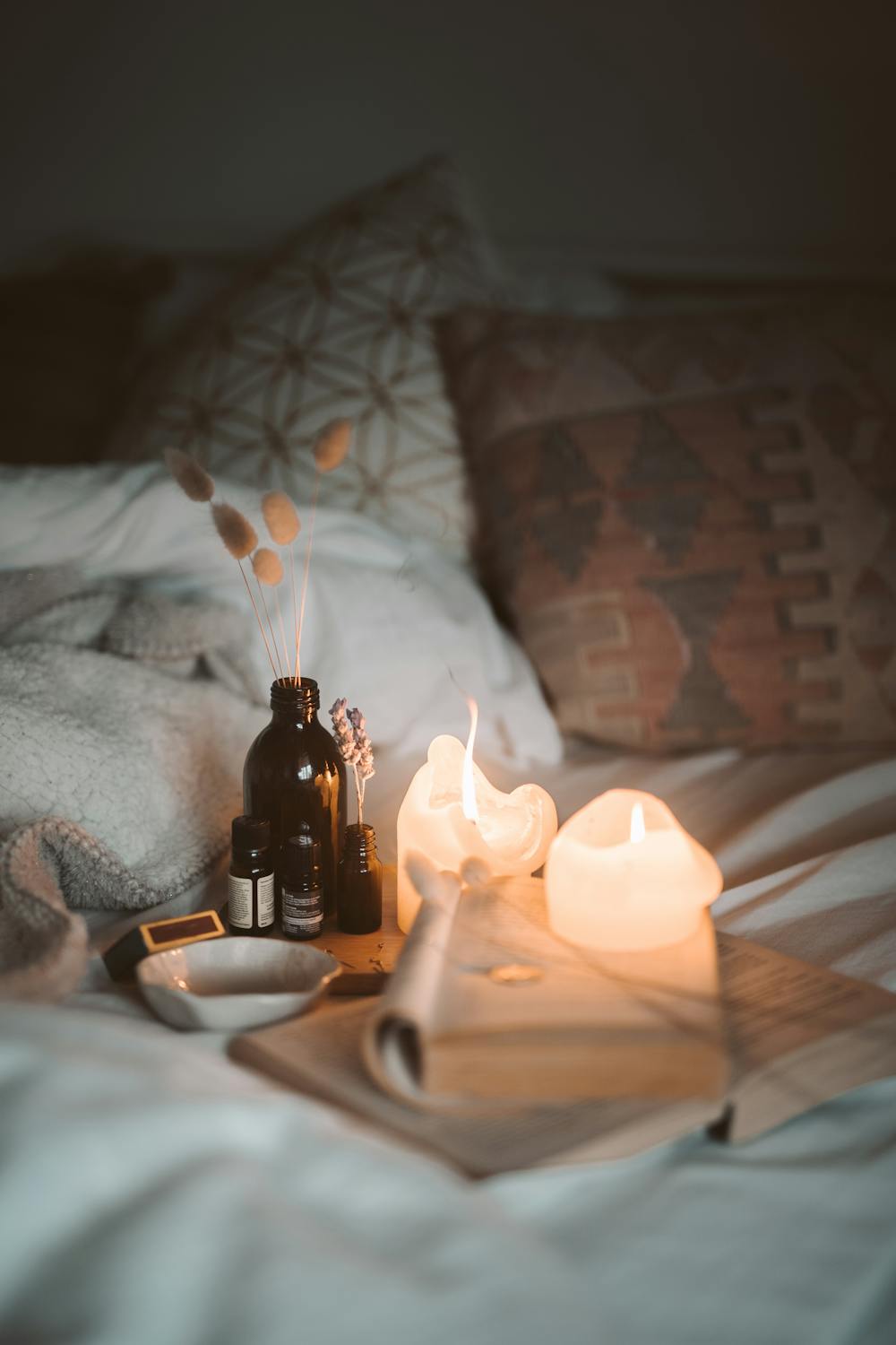 Image of books, candles, and incense on white sheets over a bed. Shows how taking time to read most important spiritual books helps us relax and reconnect with ourselves.