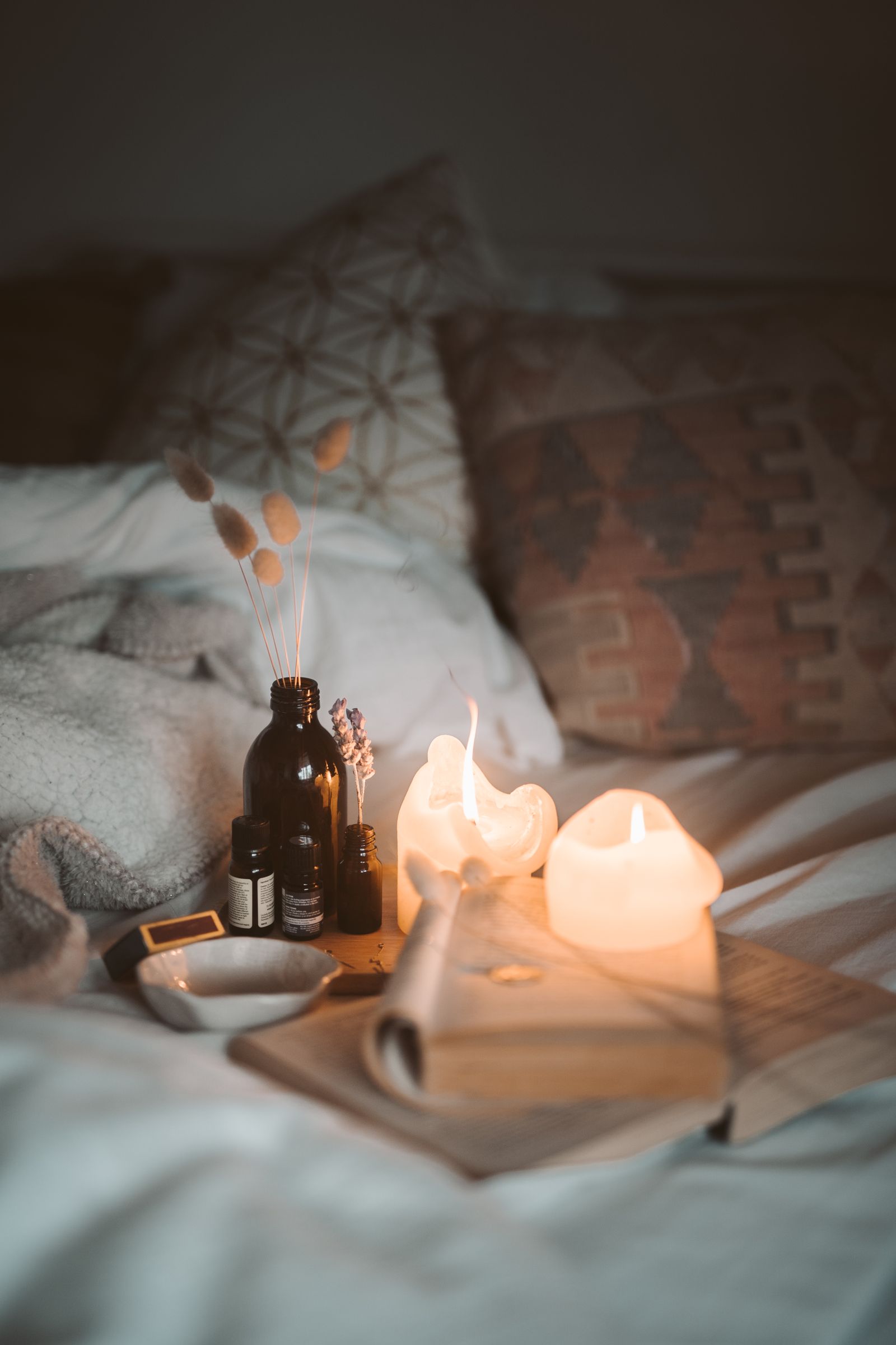 Brennende Kerzen, Buch und ätherische Öle als abendliches Ritual