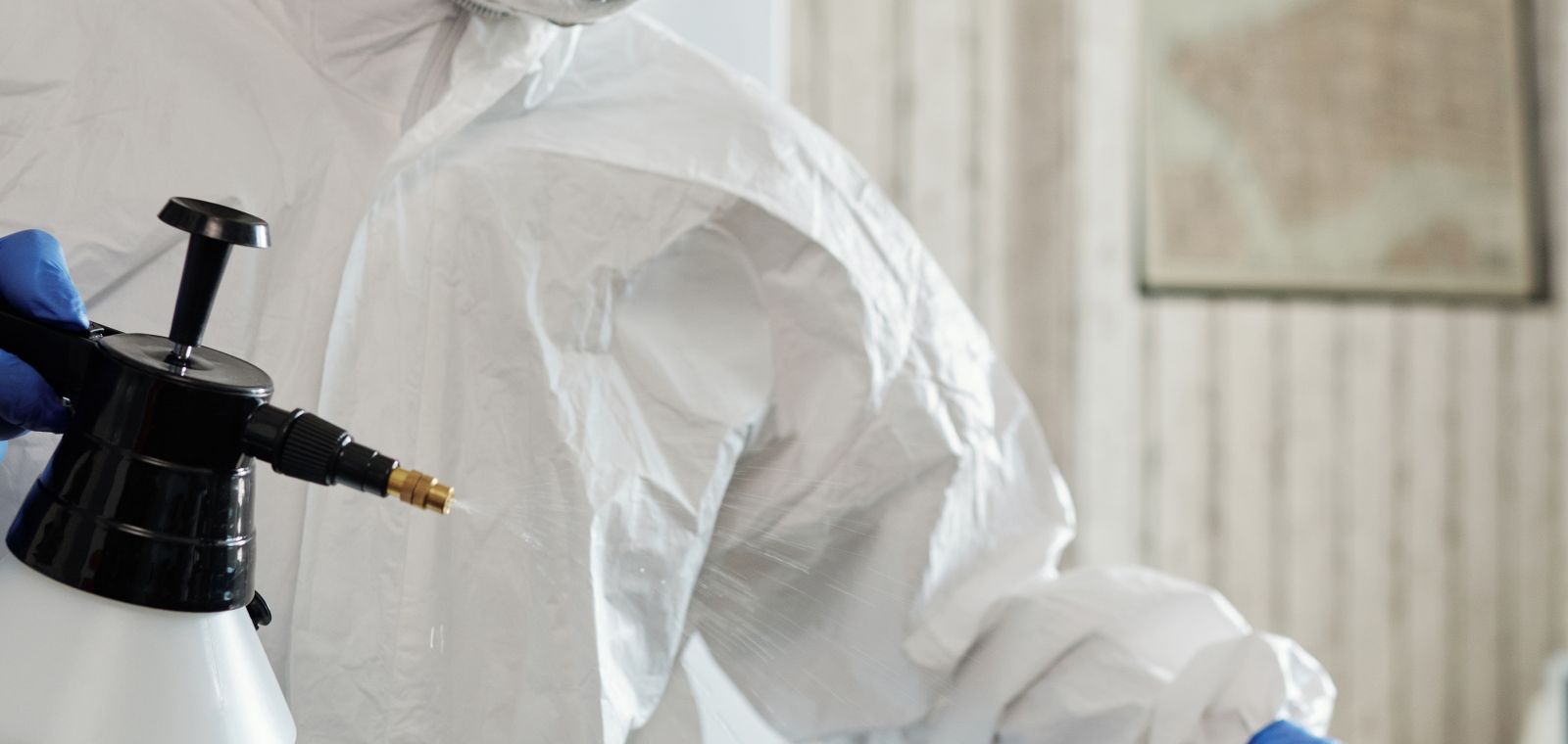 Worker in a protective suit cleaning indoor surfaces