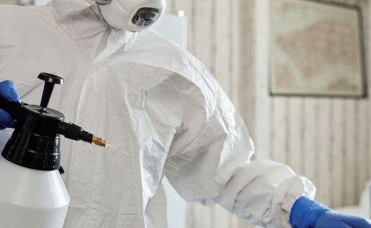Worker in a protective suit cleaning indoor surfaces